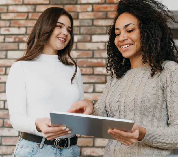 Two women discussing over a tablet.